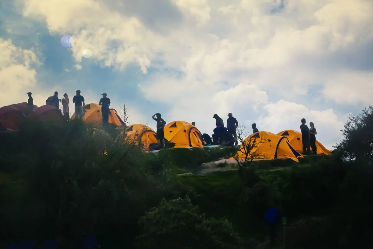 Trekkers watching the sunset beside their tents at an Inca Trail campsite