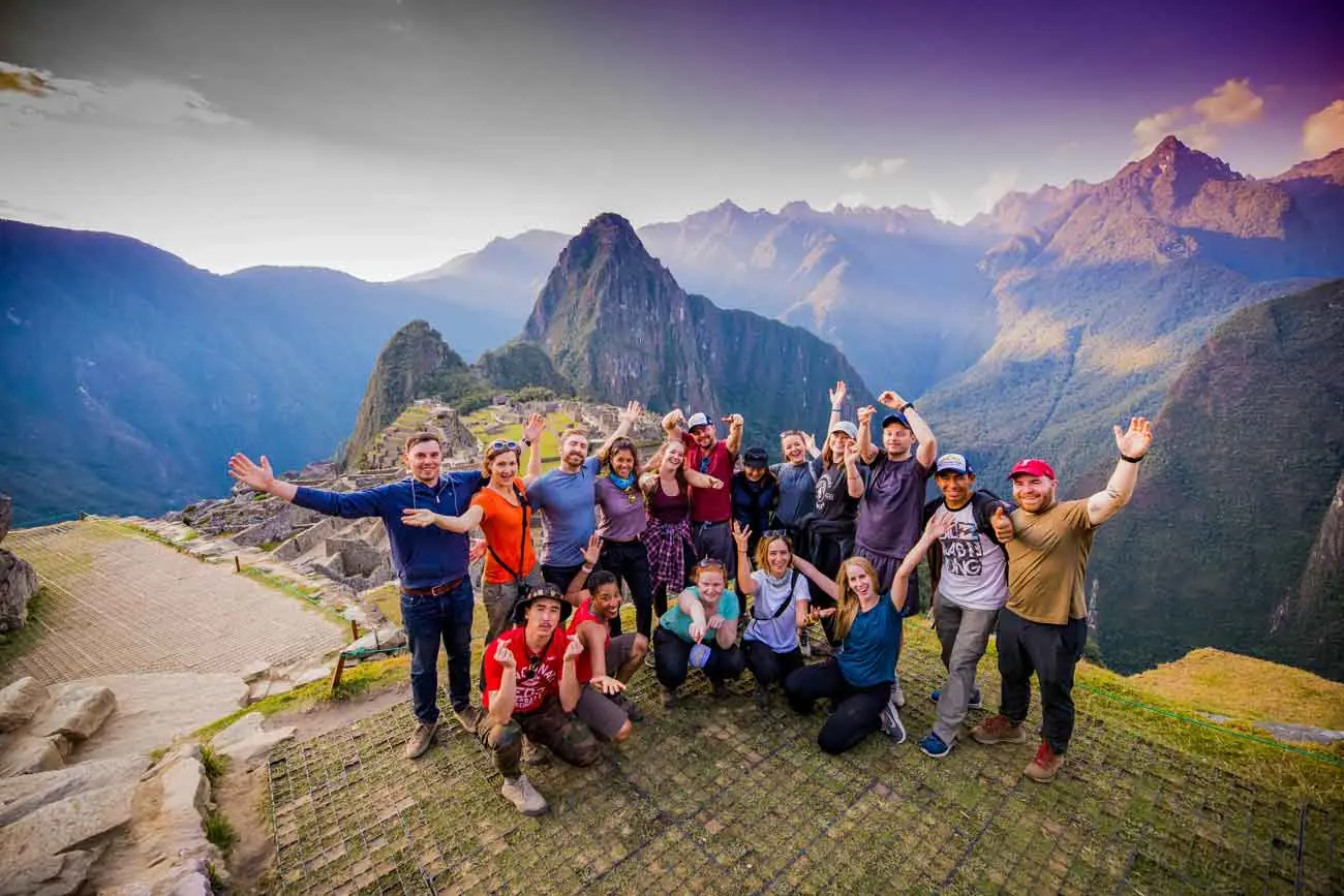 Southern Peru Explorers group celebrating at Machu Picchu with Huayna Picchu behind