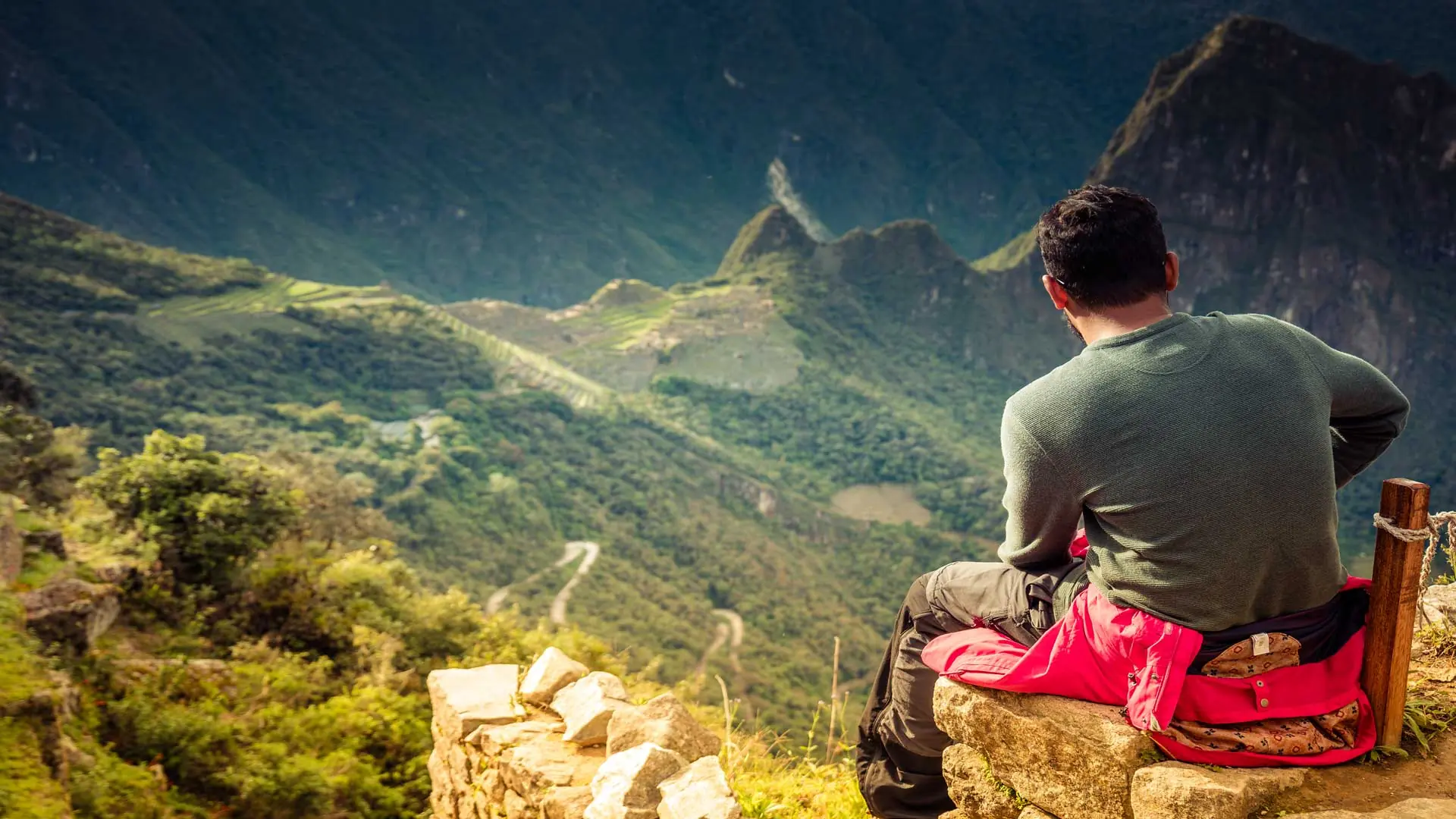 Hiker resting at Inti Punku (the Sun Gate) with Machu Picchu below on the Classic Inca Trail