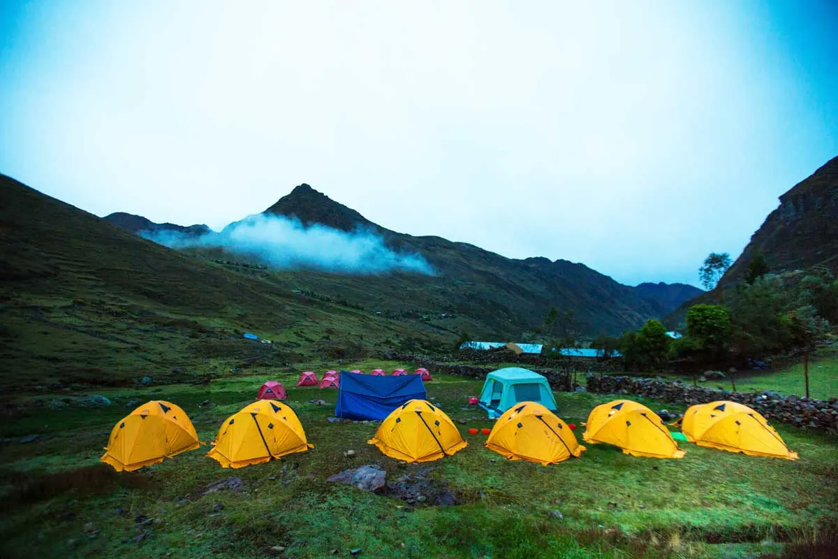 Yellow tents at a Lares Trek campsite below the mountains