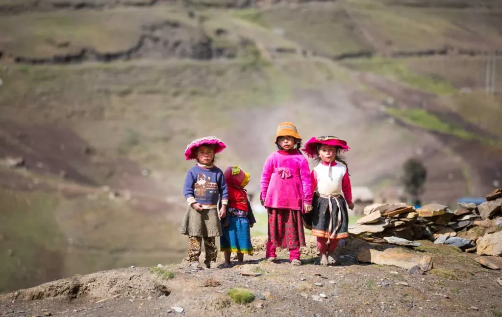 Children in traditional Andean clothing on a mountain path