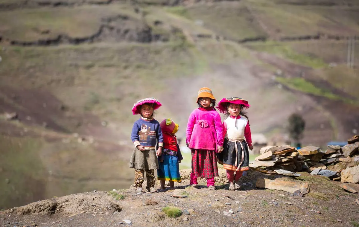 Children in traditional Andean clothing on a mountain path