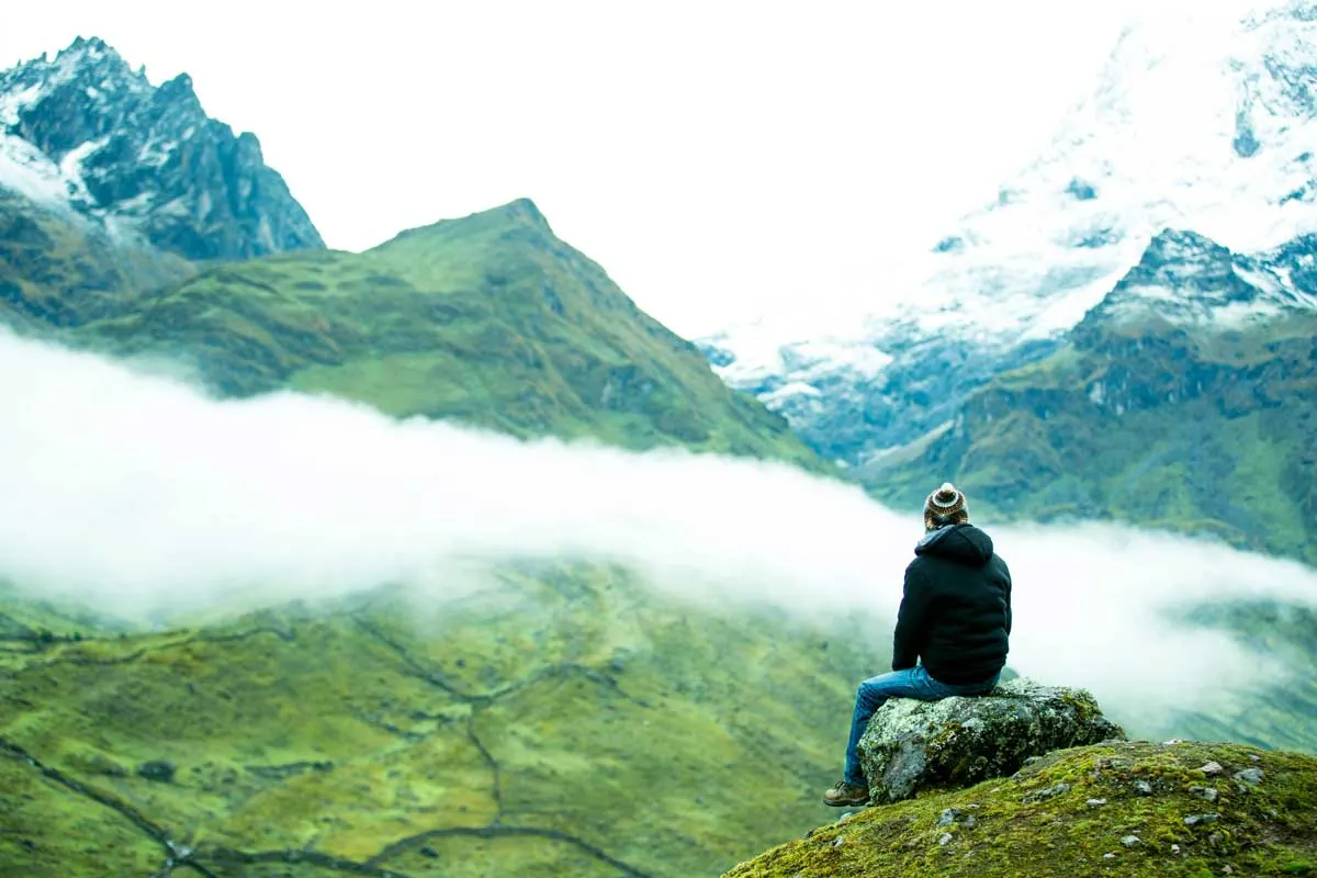Hiker sitting on a rock above a sea of clouds