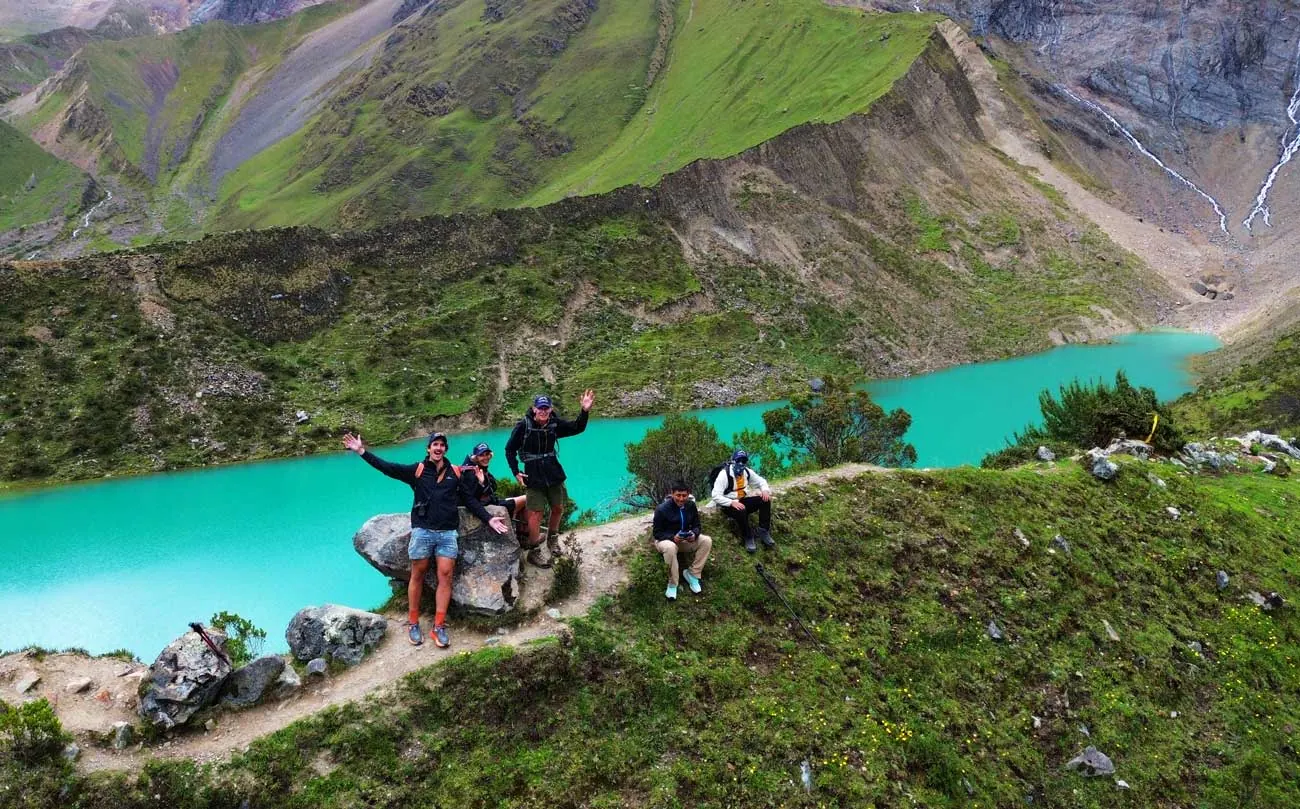 Hikers on the shore of turquoise Humantay Lake below the glacier