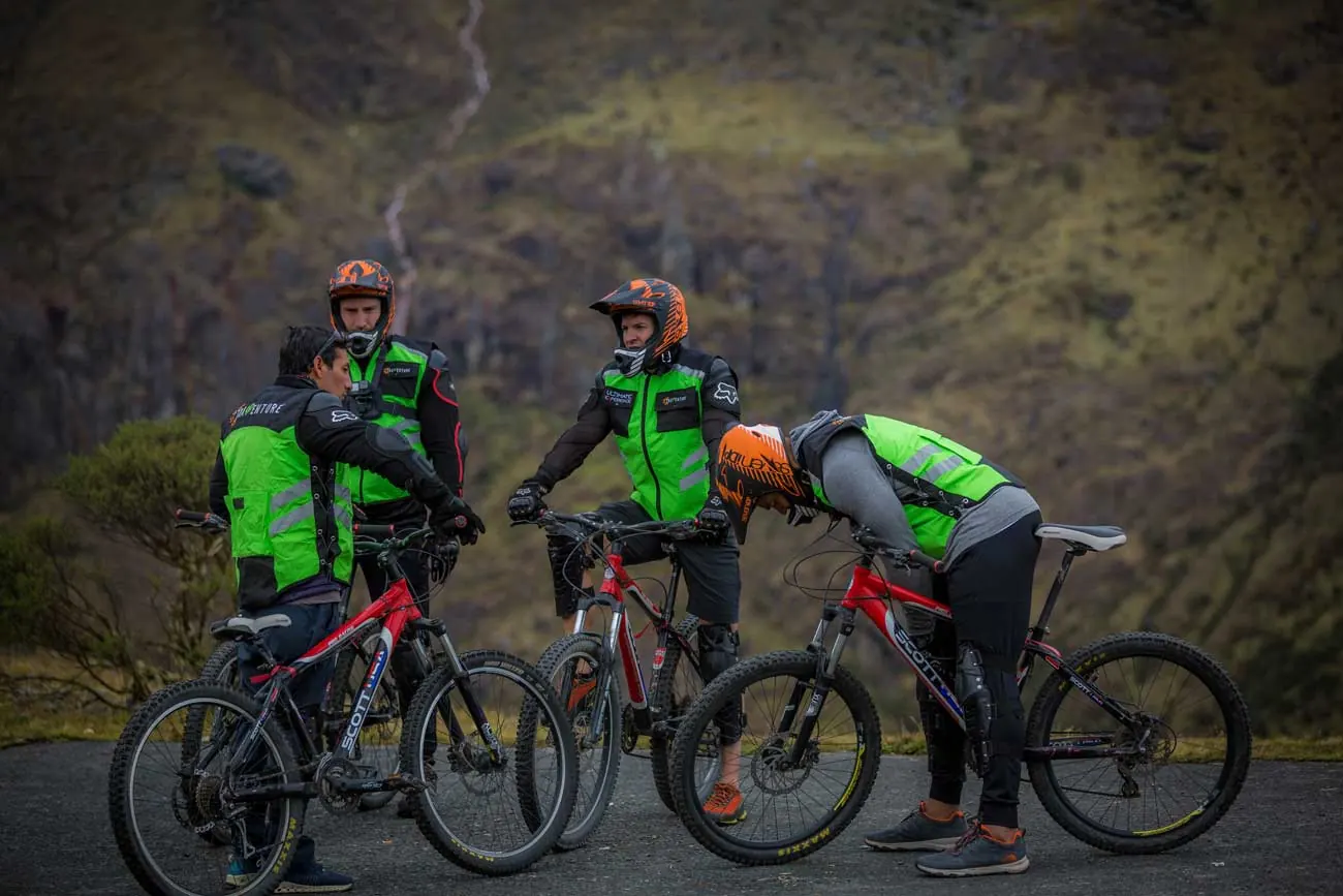 Bikers in helmets and vests resting with their mountain bikes on the road