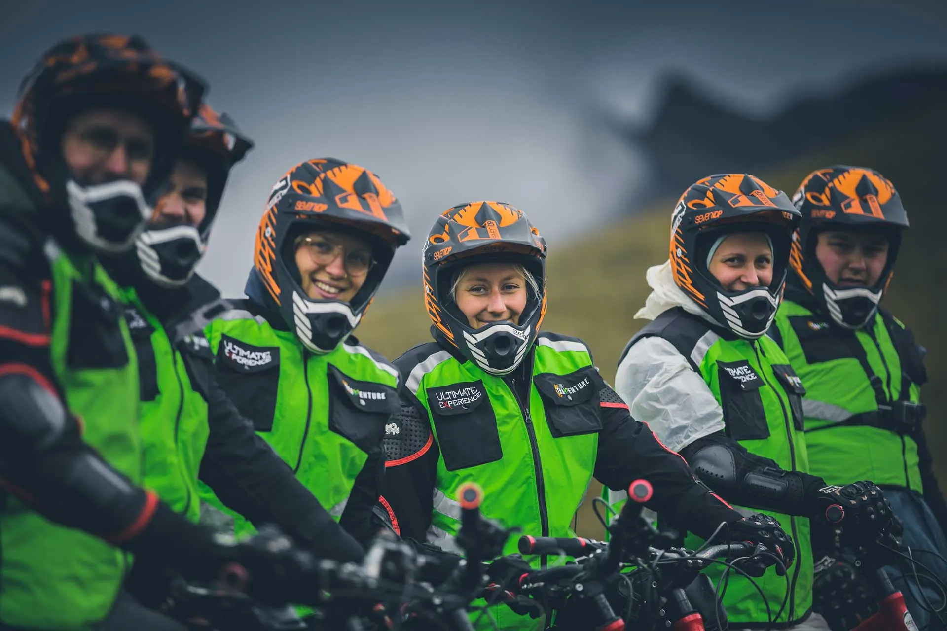 Mountain bikers in helmets and green vests ready to ride down from the Andes