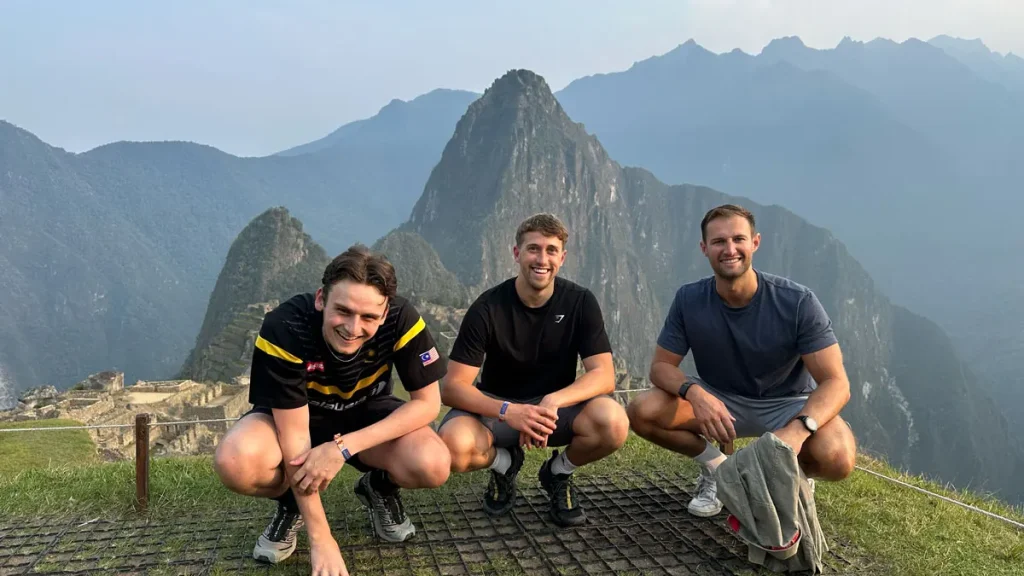 Three travelers posing at Machu Picchu with Huayna Picchu behind