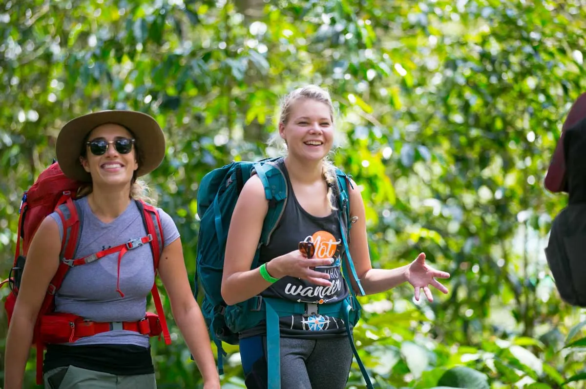 Two hikers with backpacks smiling on the trail
