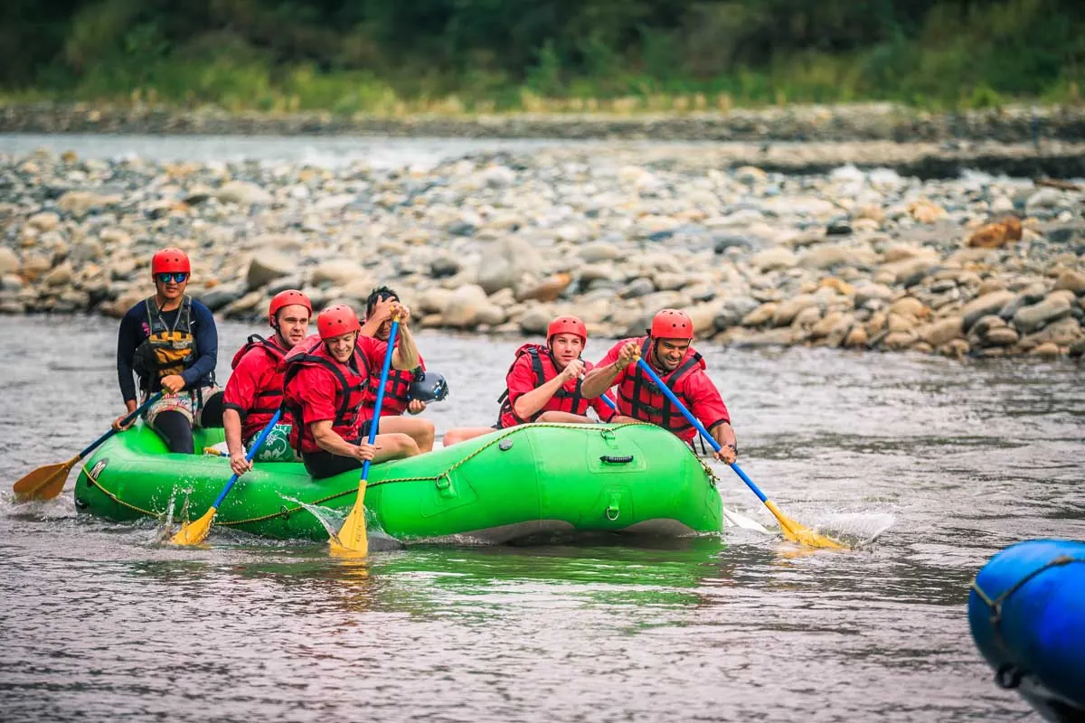 Rafters paddling a green raft on the river