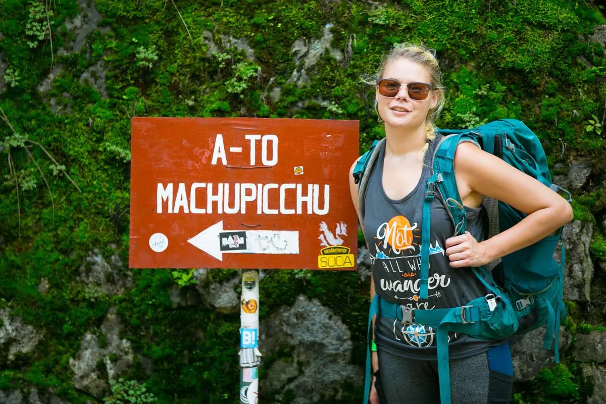 Hiker next to a sign pointing to Machu Picchu