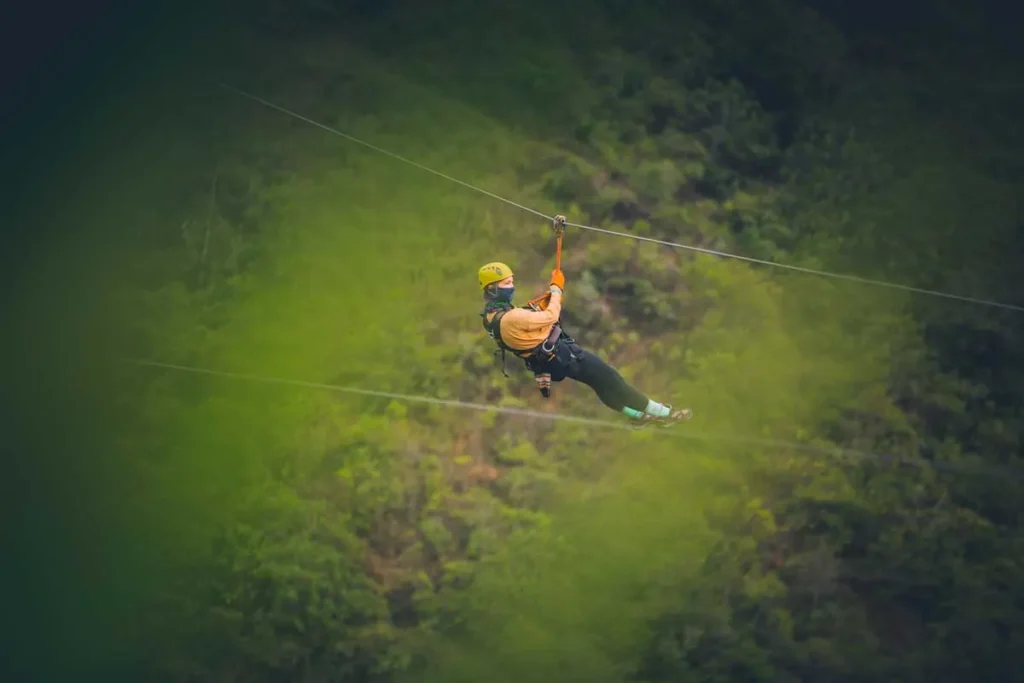Traveler on a zipline above the green forest