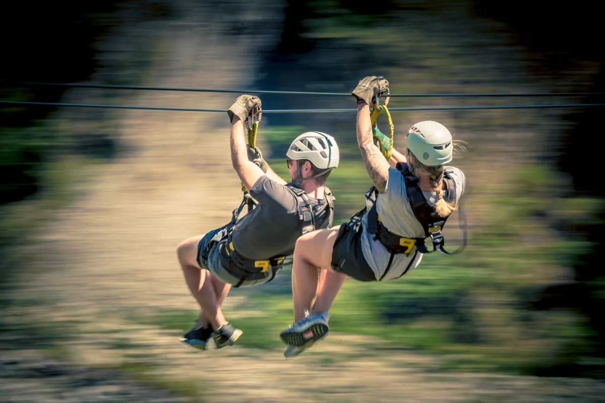 Two travelers in harnesses on a zipline