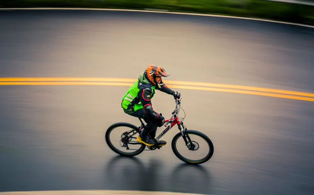 Mountain biker riding fast on a paved mountain road