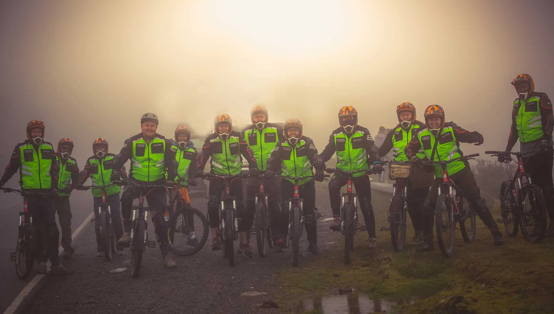 Mountain bikers in helmets and vests lined up in the mist before the descent