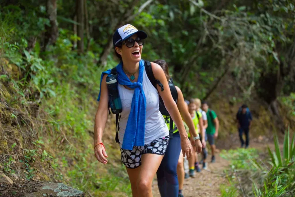 Hiker smiling on a forest trail with a group behind