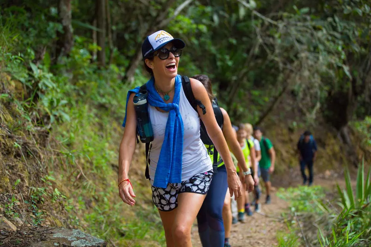 Hiker smiling on a forest trail with a group behind