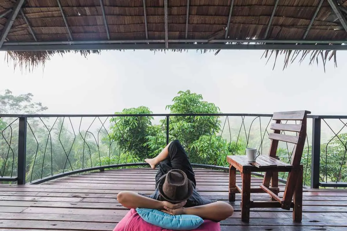 Traveler relaxing on a lodge terrace with a view of the forest