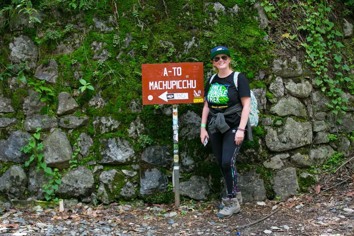 Hiker next to a sign pointing to Machu Picchu
