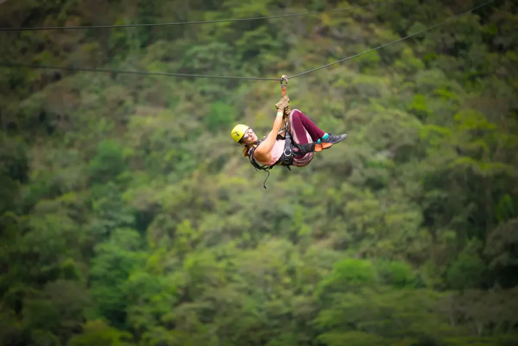 Zipline rider above the green valley