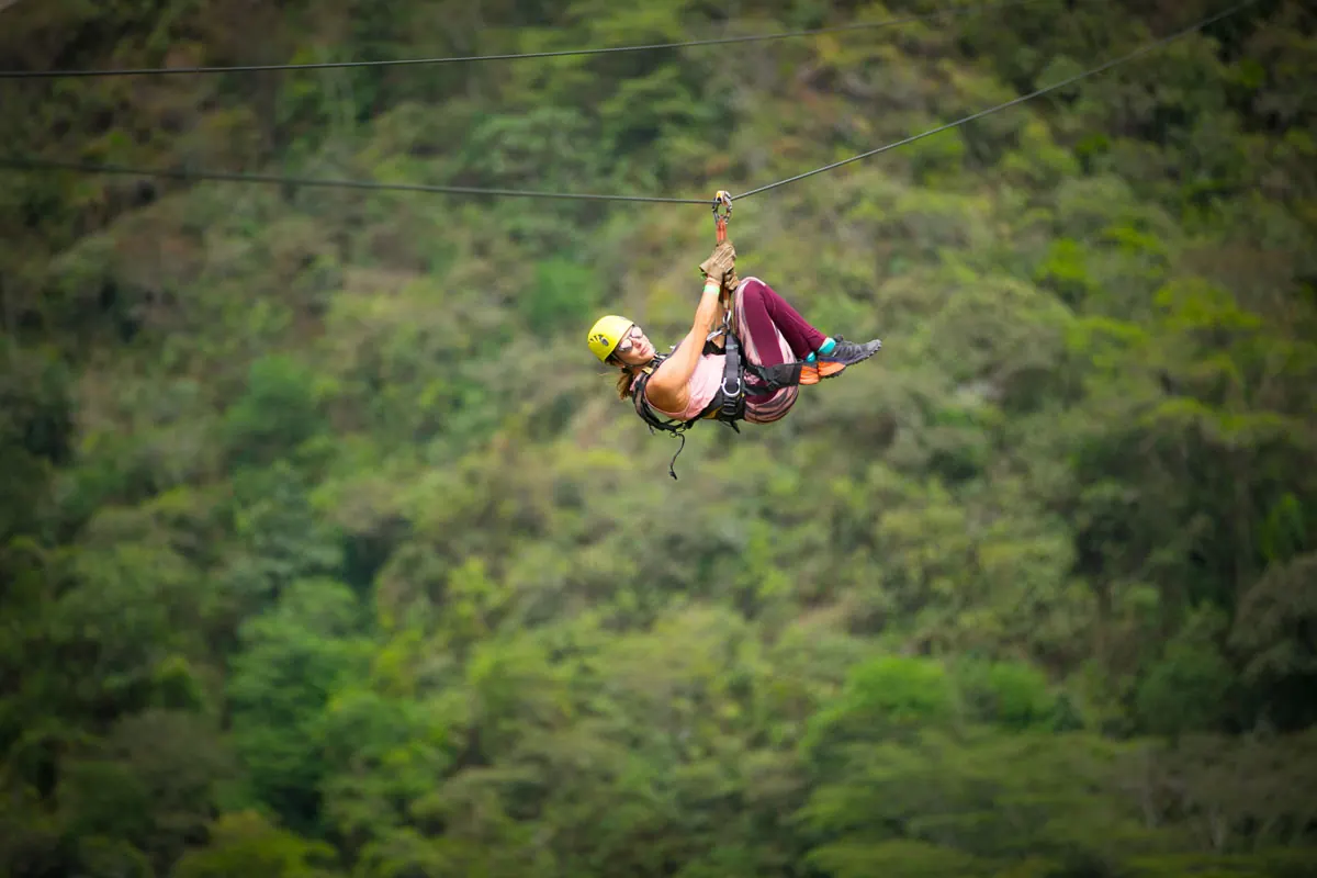 Zipline rider above the green valley