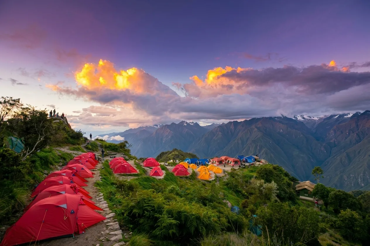 Trekking campsite with red tents at sunset in the Andes
